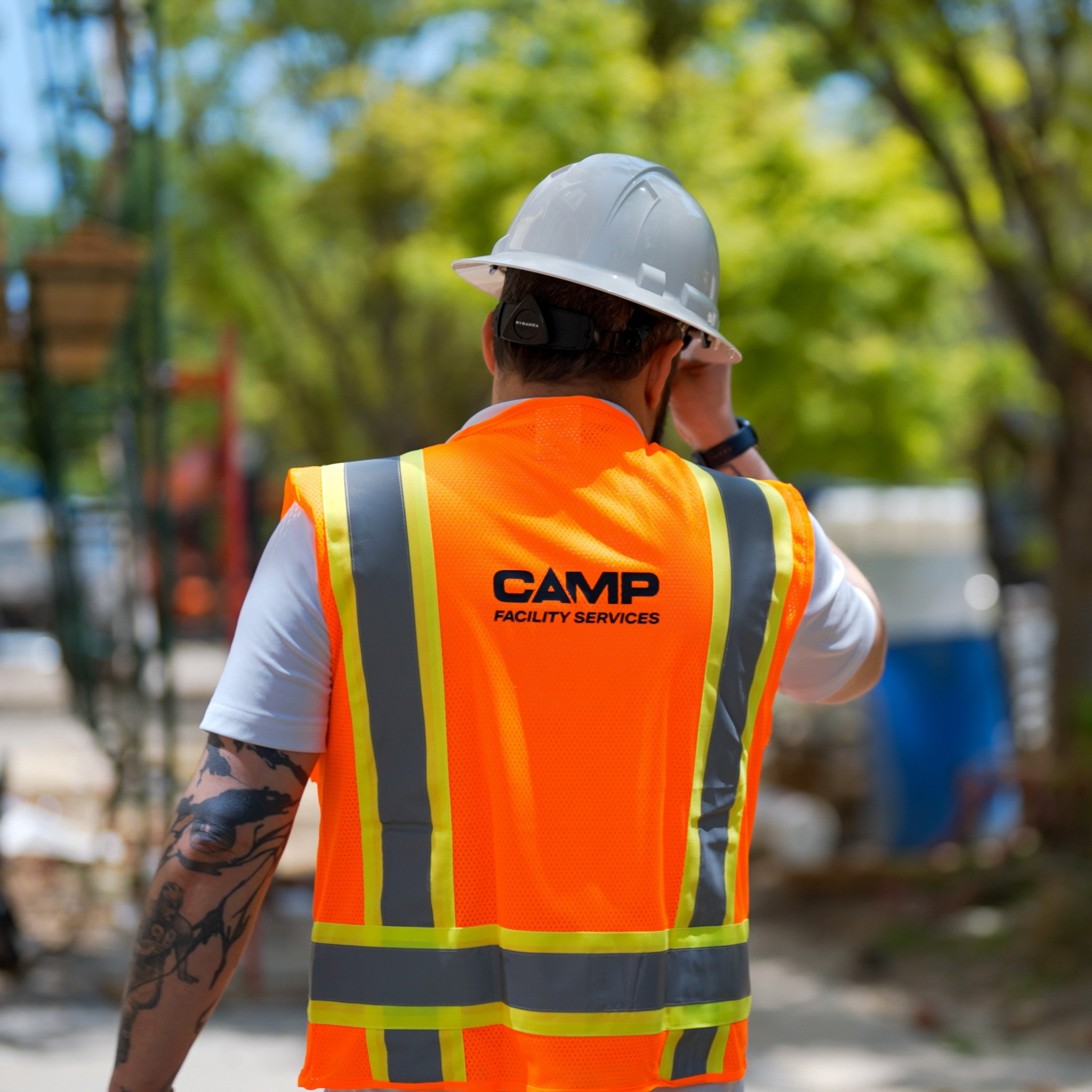 A person wearing a hardhat and a high-visibility vest at a work site.