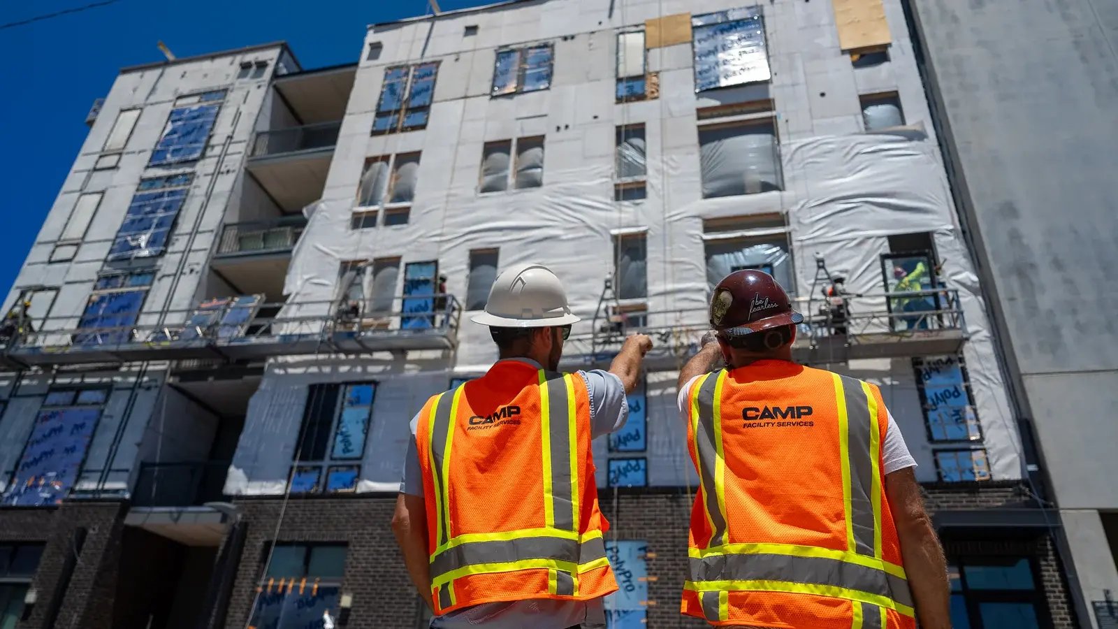 Two CAMP team members surveying the exterior of a building under renovation.