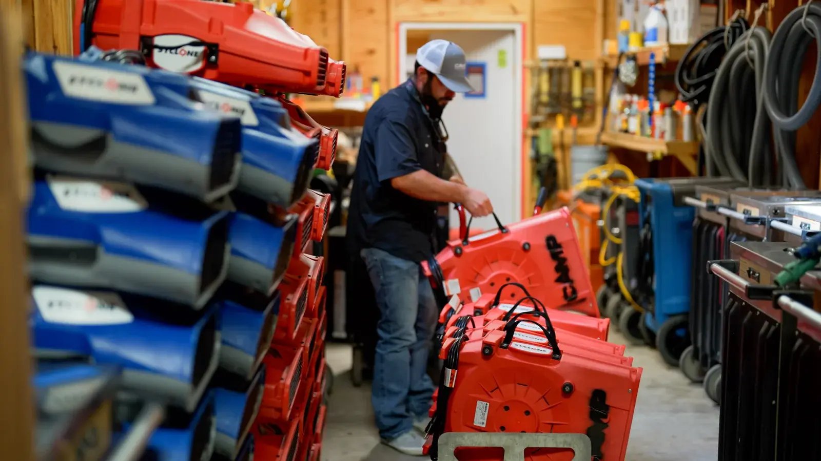 A CAMP team member preparing portable air-moving equipment in a storage area.