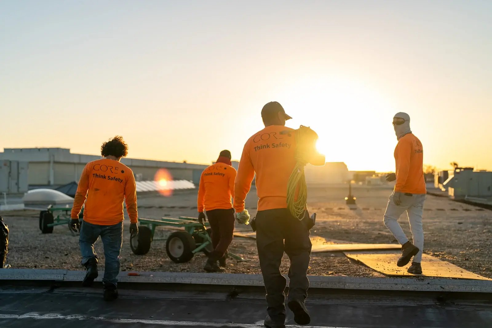 CORE Roofing crew members crossing a rooftop in warm low sunlight.
