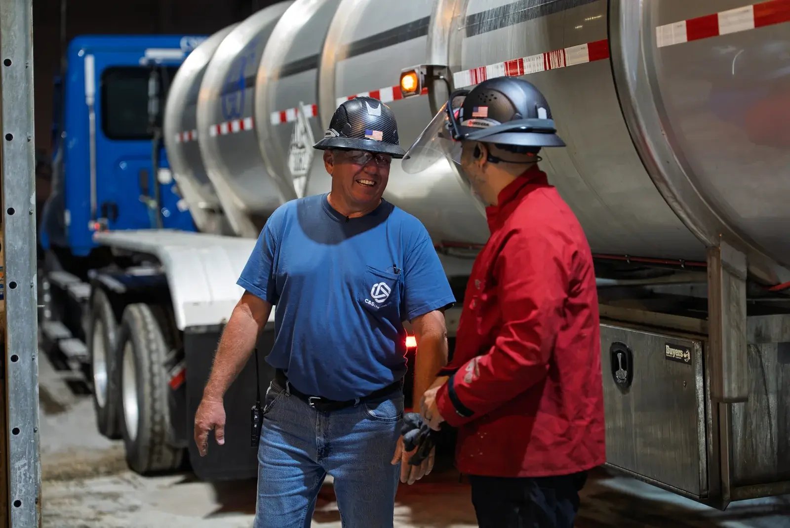Two staff members talking beside a C&S tanker trailer.