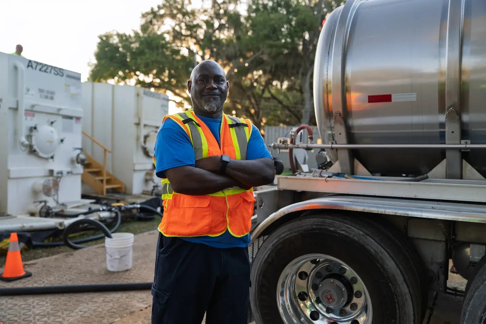 A staff member in a reflective vest standing beside a tanker trailer.