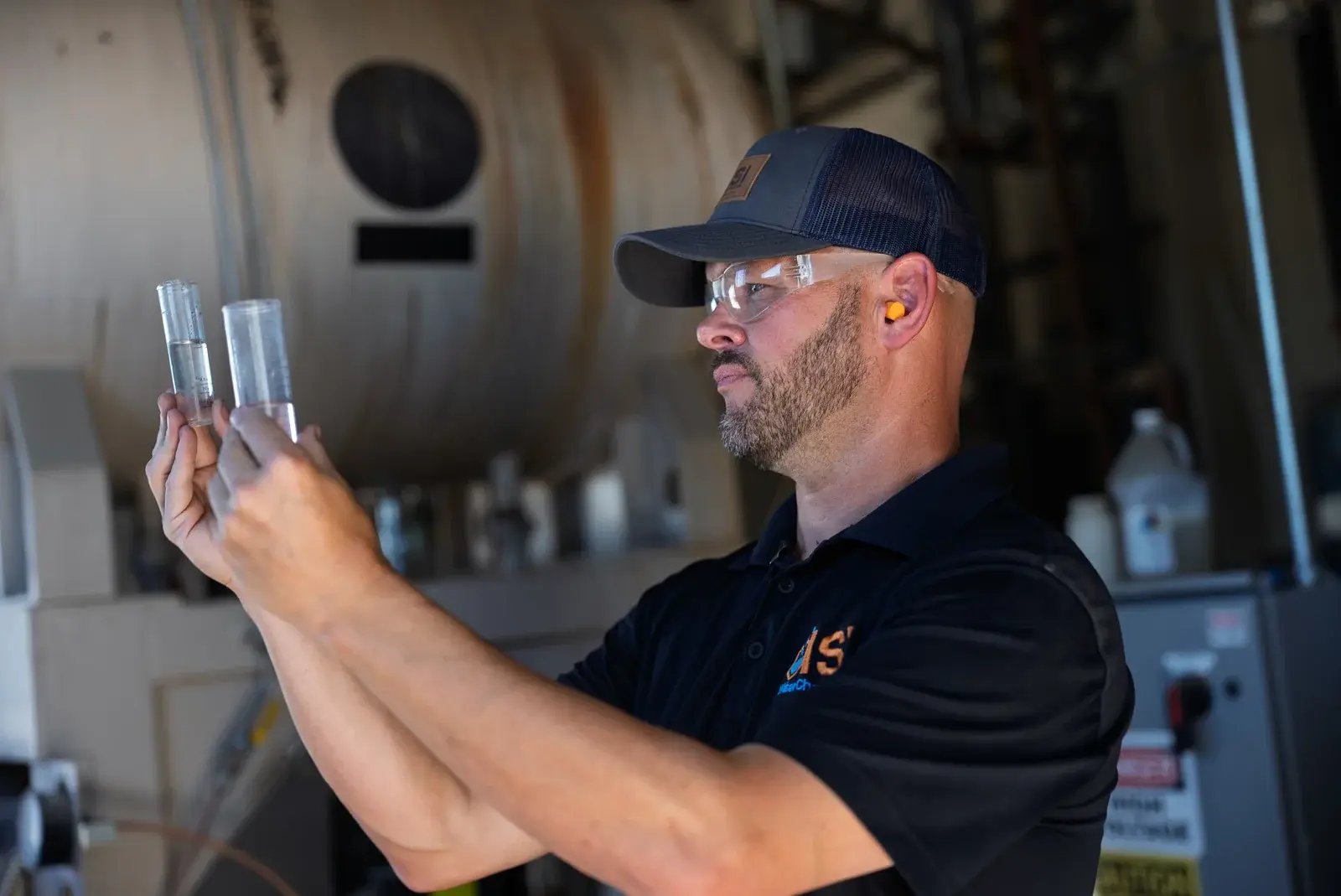 A technician inspecting glass sample tubes in a workshop.