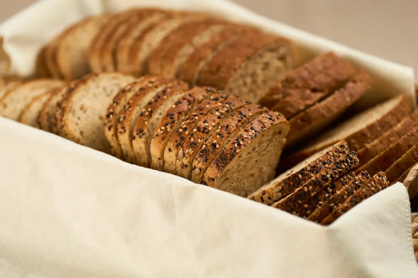Slices of seeded bread arranged in a linen-lined basket.