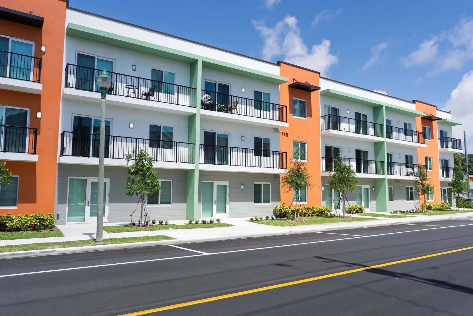 Street-level view of the completed Coleman Park apartments with green and orange balconies.