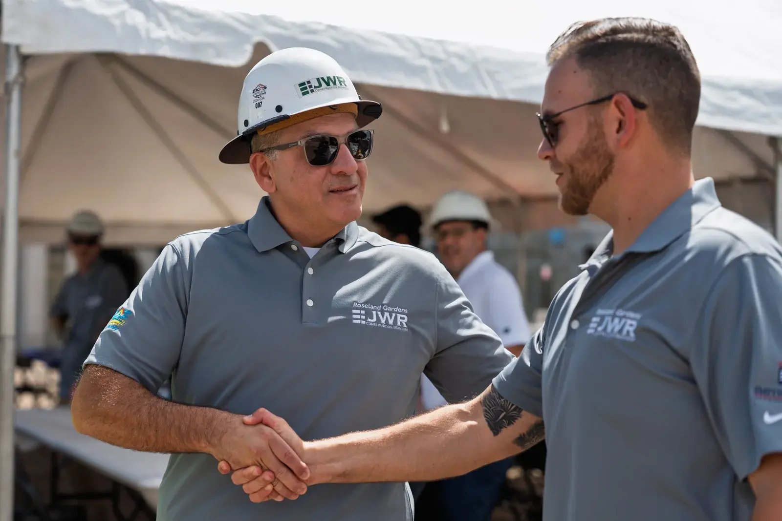 Two JWR team members shaking hands at a topping-out event.