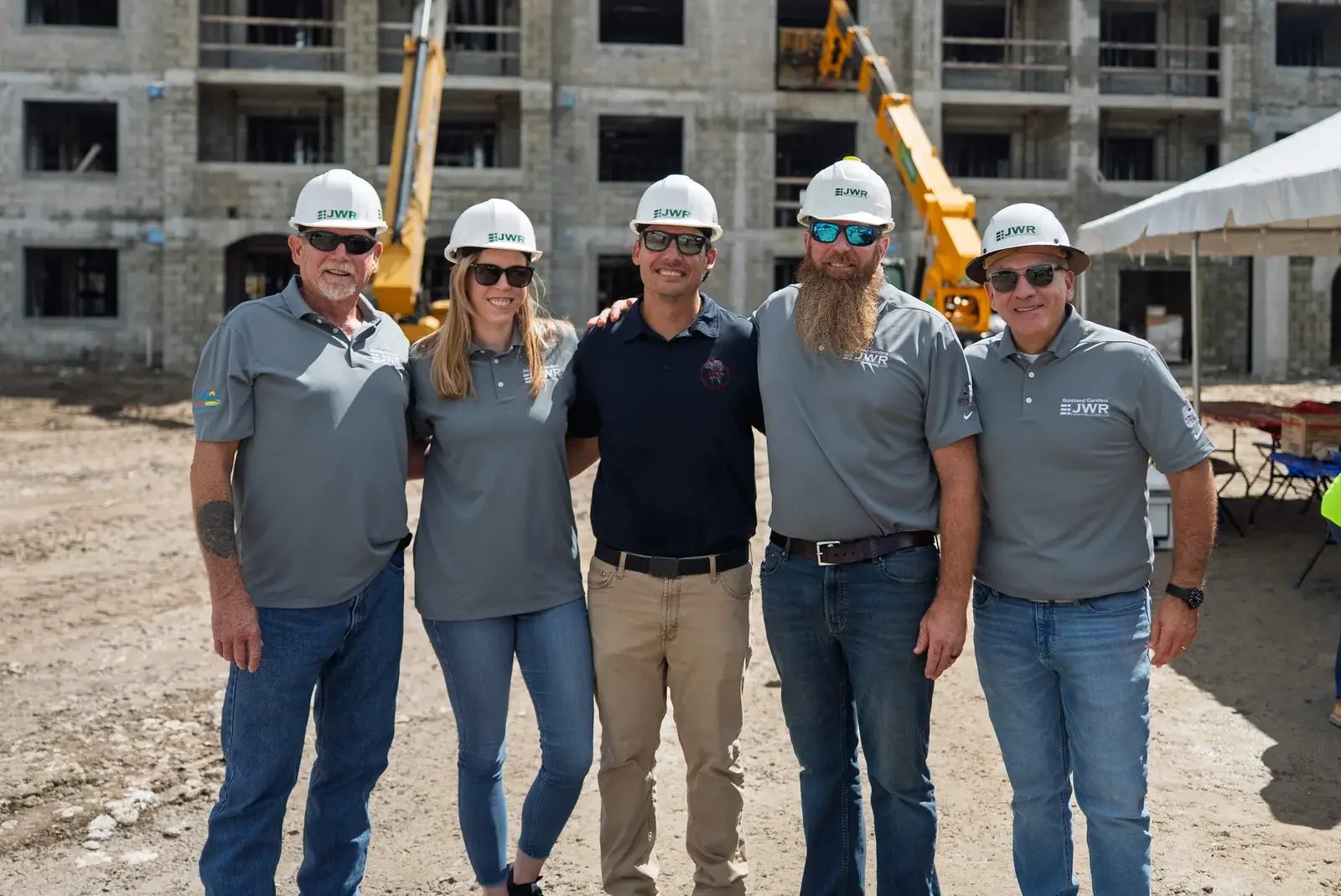 Five JWR team members standing together in front of a building under construction.