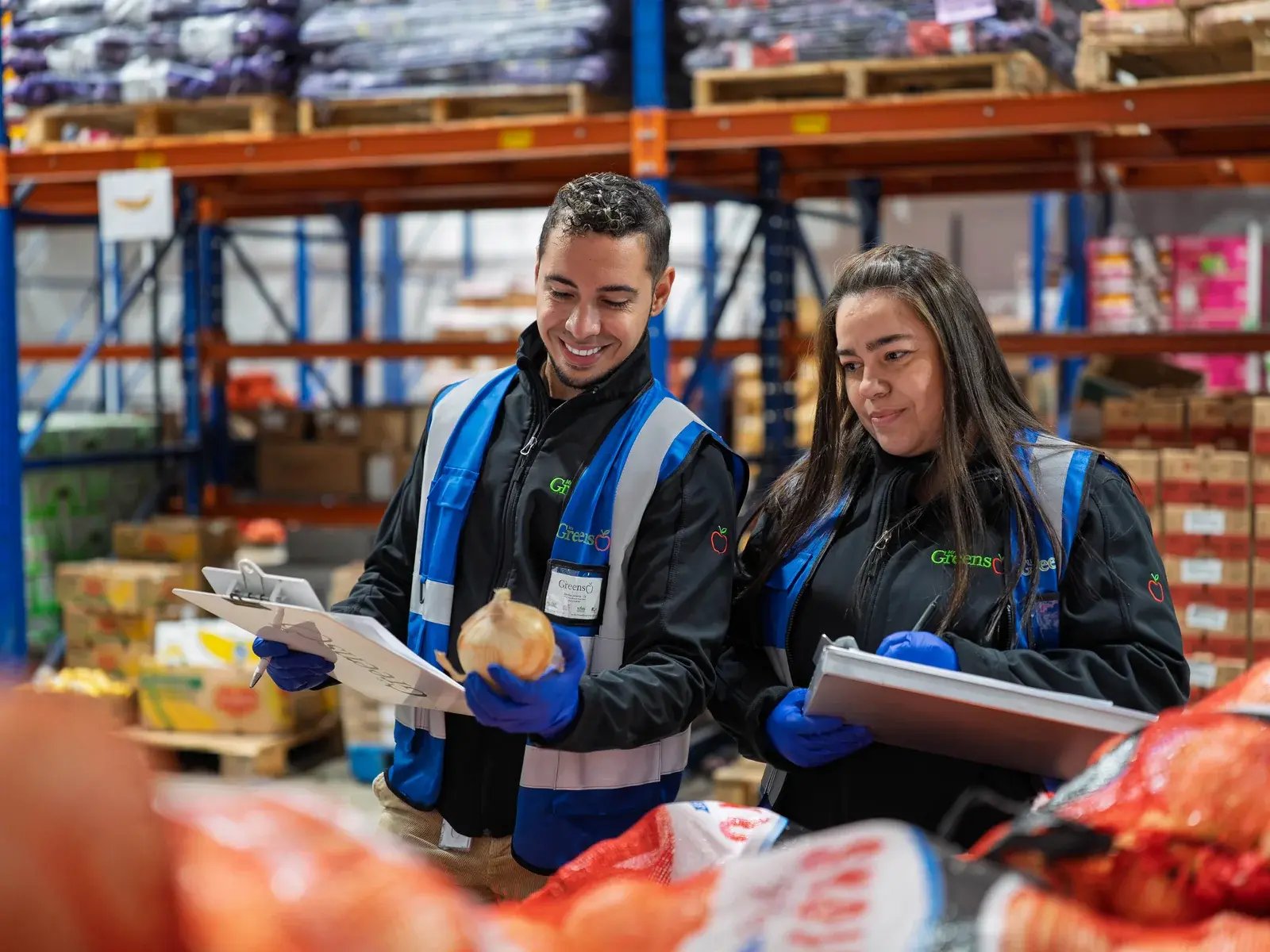 Two Mr Greens staff members inspecting produce in a warehouse.