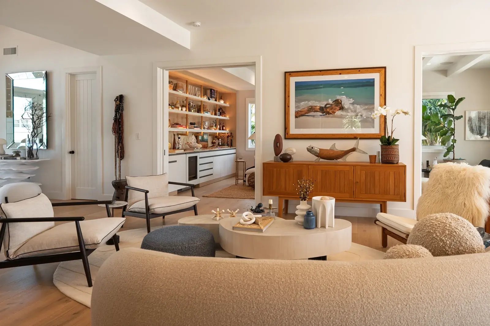 A living room with curved seating, warm wood details and a framed landscape painting.