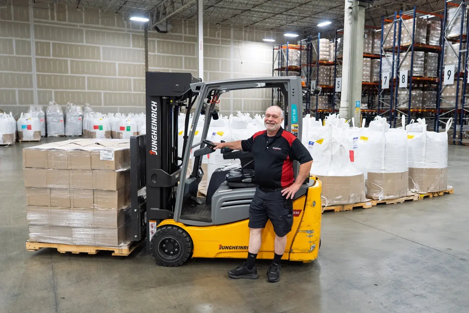 A Ronnoco staff member standing beside a forklift in the warehouse.