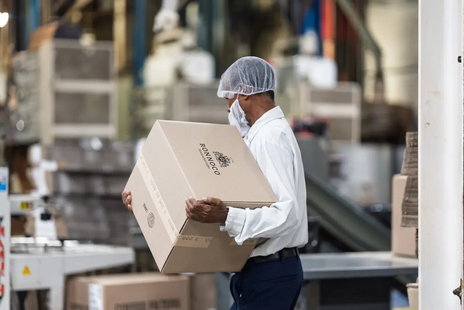 A Ronnoco staff member carrying a cardboard box through the facility.