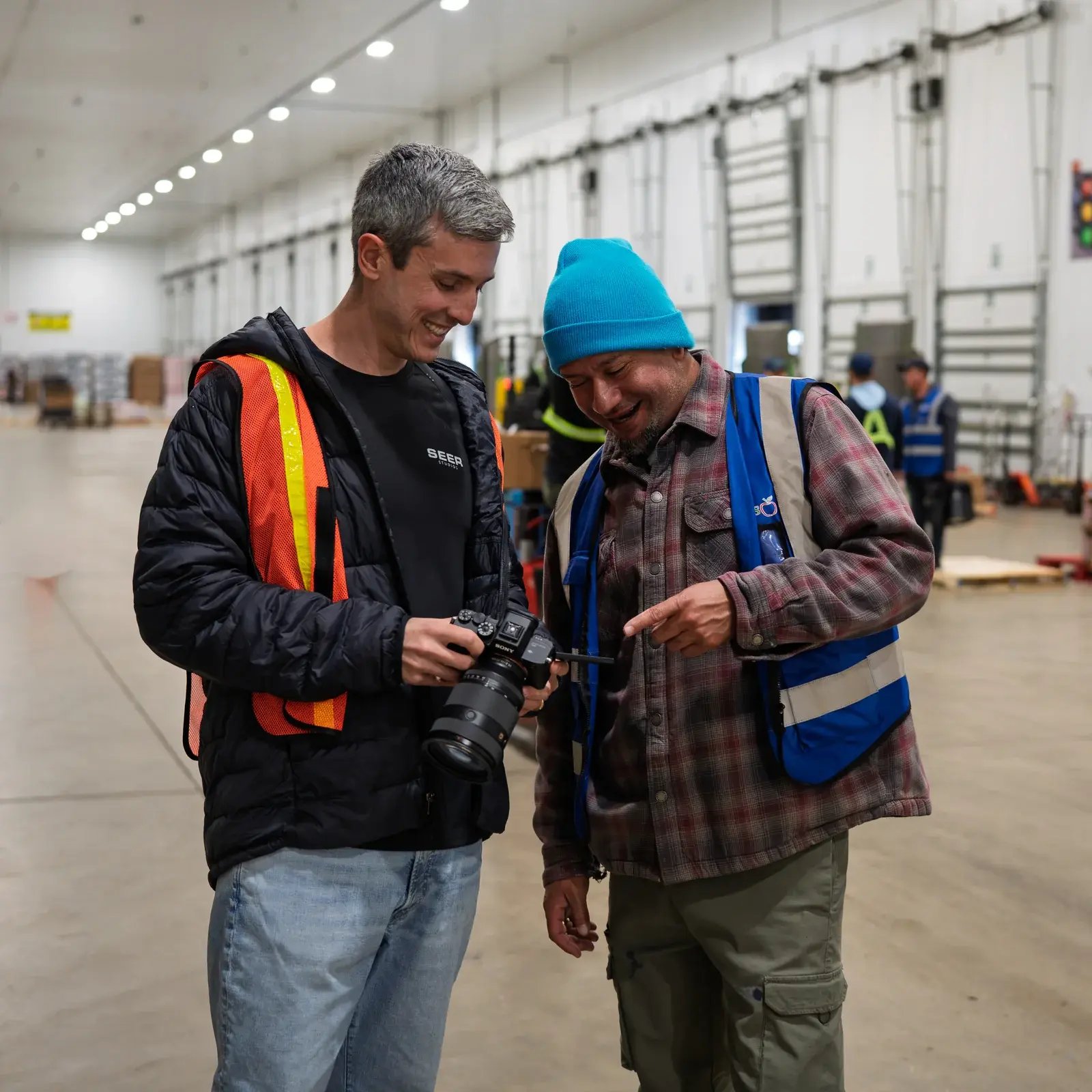 A Seer Studios photographer and a warehouse team member looking at a camera together.